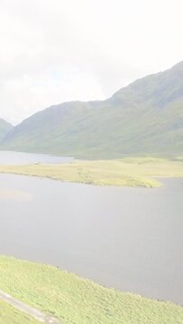 Vertical video: Red streaks reflecting on pane, view panning down-right showing lake island, track