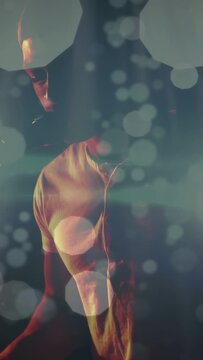 Vertical video: Camera pulling back showing singer leaning with mic as bokeh beams boosting song