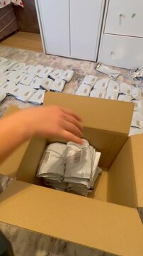 Moscow, Russia, 03.05.2026 Woman packer putting small white packages inside cardboard box. Home business shipping process for marketplace order fulfillment and online commerce logistics task.