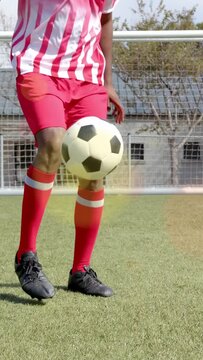 Vertical video: Male soccer player tapping ball, juggling and controlling near goal for training