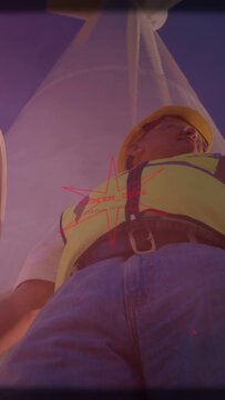 Vertical video: Camera rising construction worker checking mast for safety, red star on chest