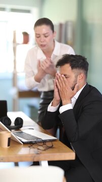 Young female boss stands in the office and scolds on a male IT department employee who did not complete her task on time. High quality 4k footage