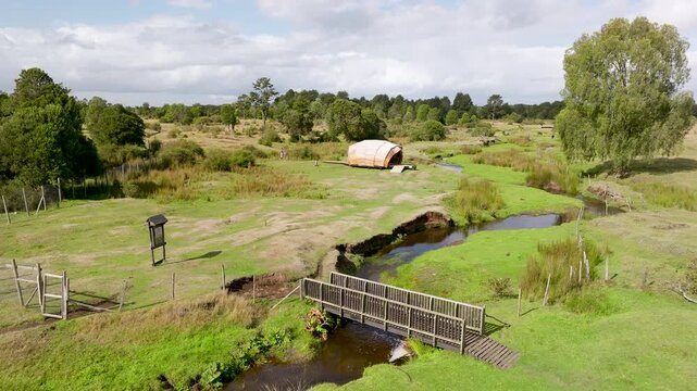 Low altitude drone shot of the Monte Verde archaeological site, showing the landscape, the stream, and a replica hut in Puerto Montt, Chile.