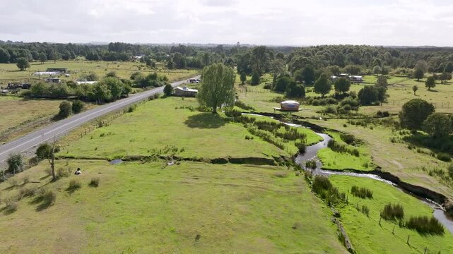 High-angle drone shot of Monte Verde archaeological site in Puerto Montt, showing the visitor center, the main road, and the Chinchihuapi stream.