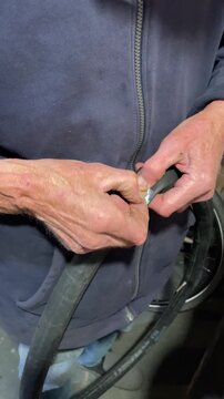 Experienced mechanic carefully applying a patch to a punctured bicycle inner tube, demonstrating the process of fixing a flat tire in a workshop with professional skill and precision