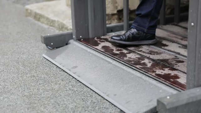 Close-up of Male Legs in Black Leather Shoes Stepping on a Padded Entry Ramp