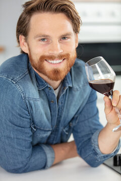 smiling man holding red wine glass at home