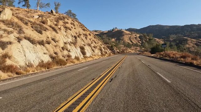 Golden morning sunshine on scenic, rustic highway in Sierra Nevada mtns