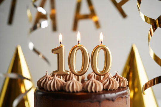 Chocolate 100th birthday cake with flickering candle. Celebration of longevity and reaching a century of life