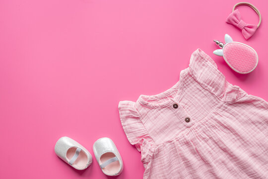Baby girl pink cotton muslin dress and unicorn-shaped accessories, top view. Kids stylish summer clothes