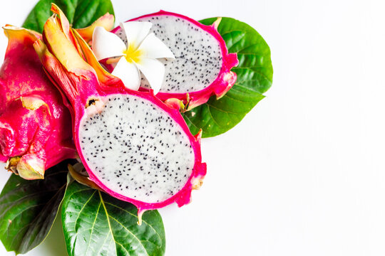 Two pitaya fruits with green leaves on white table. Ripe dragon fruit or pitahaya. Tropical fruits food, top view