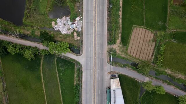 High-quality 4K aerial nadir view of a rural road junction, featuring vehicle movement and green agricultural fields, highlighting regional logistics and infrastructure.