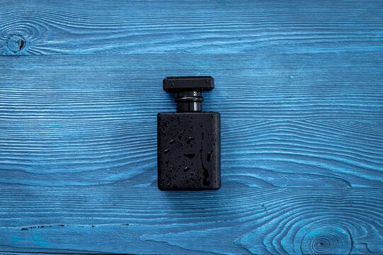 Stylish black perfume bottle with water drops. Male fragrance concept