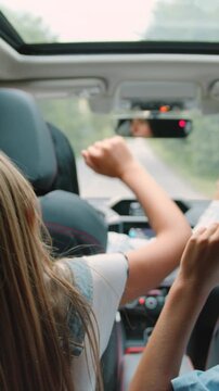 Two little kids listens enjoys music and dancing while road trip. Children are playing in the car. Concept of journey. Slow motion.