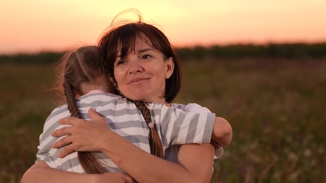 mother woman parent female, child girl kid childhood outdoors, Mother and daughter hugging in a field, Woman embracing child at sunset, Family love and togetherness, Warm evening outdoors, Parent and