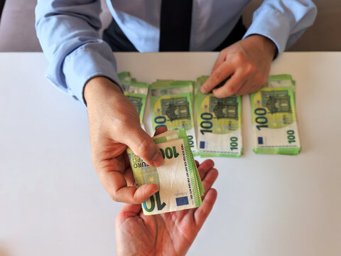 Overhead view: A businessman counts hundred-euro bills to make a payment. The scene symbolizes banking transactions, cash advances, investments, or illegal payments (kickbacks).