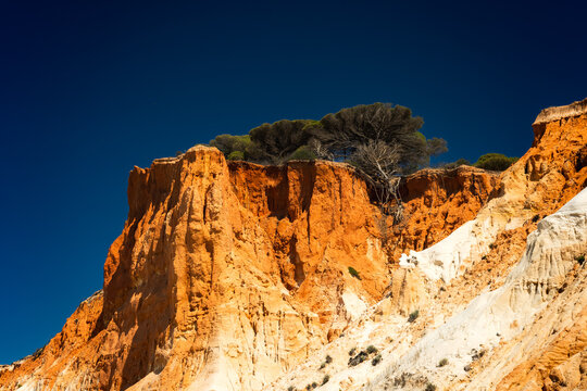 Dramatic orange cliffs overlooking the deep blue sky in the Agarve region of Portugal