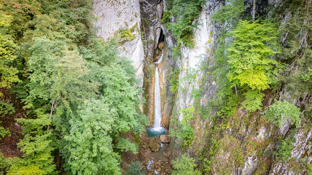 Aerial view of Grandvillard Waterfall cascading through a narrow rocky gorge surrounded by dense green forest and steep cliffs Grandvillard, Fribourg, Switzerland.