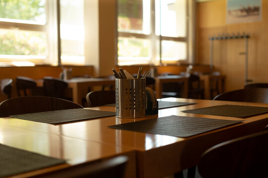 Wide communal table with inviting illumination. Expansive collective eating space featuring central stand and warm ambient lighting for social gatherings