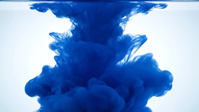 Blue ink cloud dissolving in water on white background