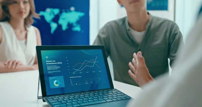 Closeup group Asian businesspeople work together discuss plan idea with investment profit sale statistics in business meeting in office. Financial generation z team brainstorm on e-Commerce project.