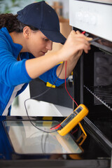 Obraz premium young repairwoman examining kitchen oven