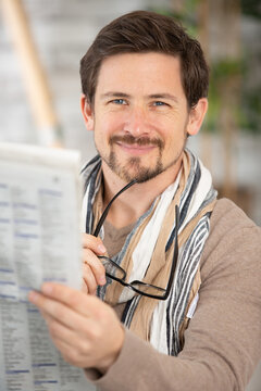 man in glasses reading newspaper at home