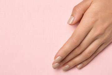 Naklejka premium Elegant Nude Manicure On Hands Against Pink Surface