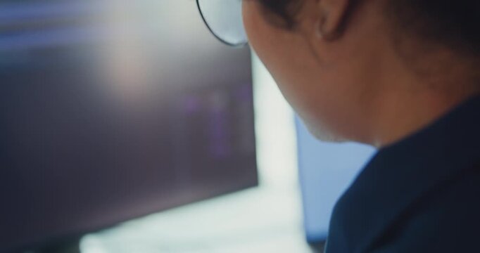 Close-up young Black female robotics engineer coding AI software for robotic arm in laboratory. Embedded system, firmware testing, machine learning, industrial automation, future technology concept.