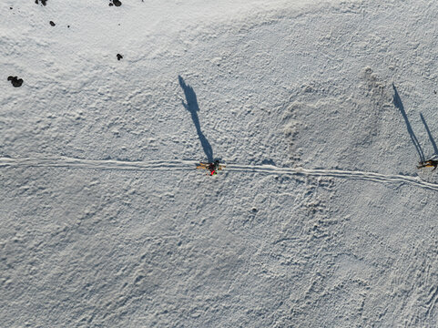 Aerial view of Mount Etna South Slope with a skier casting a long shadow on the white snow and volcanic rocks Nicolosi, Sicilia, Italy.
