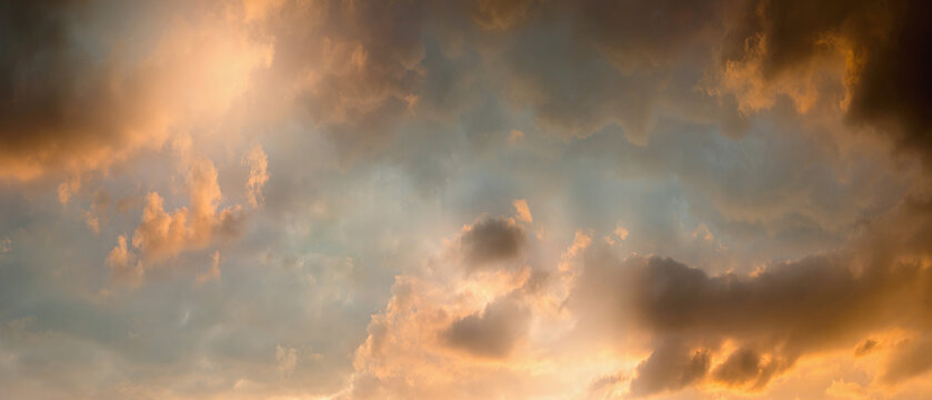 Wide panoramic Stormy dramatic sunset sky  covered clouds and sun is shining through them. clouds orange and sky is beautiful pink fnd blue shade