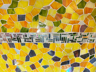 Close up of fish scales or snake scales mosaic tiles in shades of yellow, green, and orange colors with amazing carved details. Seamless background texture. © TMR Studio