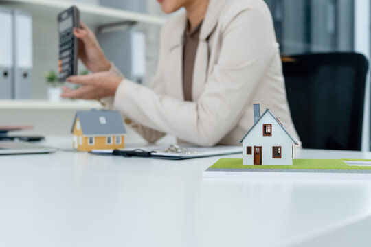 Real Estate Agent Showing Calculator to Laptop Camera at Office Desk