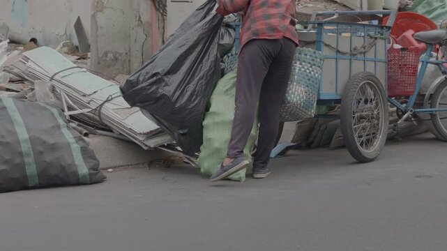 Vietnamese woman collecting recyclables on a tricycle with blurred city traffic in foreground