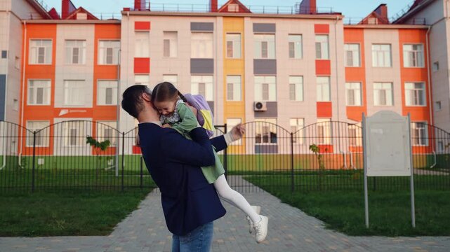 kid child with school backpack runs along road his father. father spins child girl daughter arms. super hero game. father day happy family. childhood dream daddy daughter. schoolgirl runs hug her dad.
