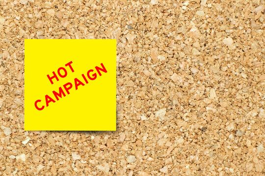 Yellow note paper with word hot campaign on cork board background with copy space