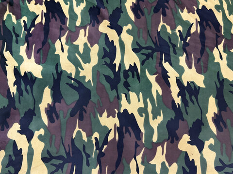 Graphic background of army clothes pattern in mix of green, beige, and brown color. Similar to army or military uniform clothes pattern. Seamless background texture.
