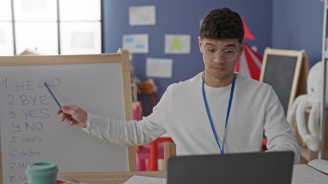 Man teacher pointing at whiteboard with pointer and visible hand in classroom building; concentration.