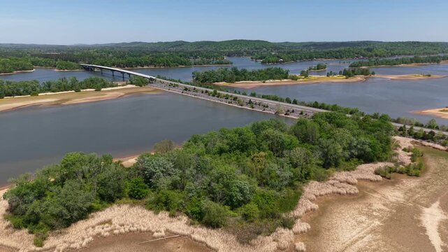 Overhead drone footage of a large sandy riverbank and wooded river island along the Tennessee River near Georgetown Tennessee with the wide river stretching into the distance and blue summer sky