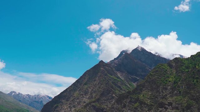 Landscape shot of clouds above the snowy Himalayan mountain peak against the blue sky as seen during the summer season in Lahaul and Spiti district, Himachal Pradesh, India. Natural background.