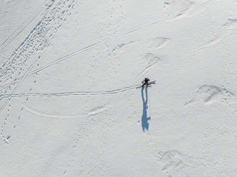 Aerial view of the south slope of Mount Etna with a person ski touring across the snow with long shadows in Nicolosi, Sicilia, Italy.