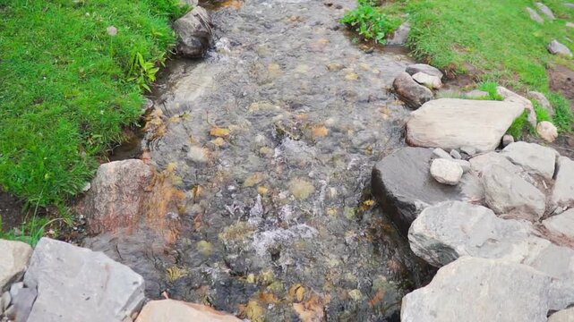 Closeup slow motion shot of a clear water stream in the Himalayan mountains as seen in Sural Bhatori at Pangi Valley in Chamba district, Himachal Pradesh, India. Scenic natural view of river stream.