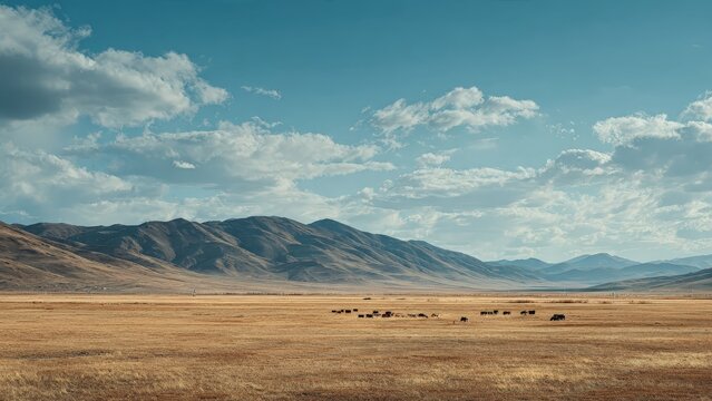 Open Plain with Grazing Cattle and Mountain Range Under Blue Sky