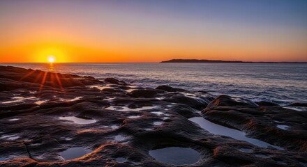 Naklejka premium Stunning sunset over a rocky coastline with tide pools and calm ocean
