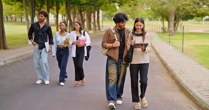 Indian young adult gen z busy boy girl guys use tab look screen talk share new online e learning study plan pupil female male man group speak funny gossip enjoy break day have fun joy park