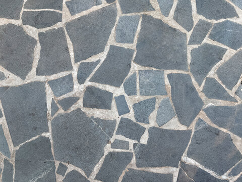 Natural random cut dark grey flagstone flattened on a surface. Or a series of cobble stones but flattened and paved seamlessly, for floor or wall finishes. 