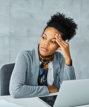 Portrait of a young black businesswoman havin a headache, or being stressed at work in the office. Overworked and sleepy frustrated business person