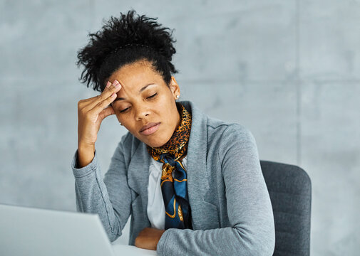 Portrait of a young black businesswoman havin a headache, or being stressed at work in the office. Overworked and sleepy frustrated business person