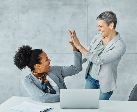Portrait of two young businesswomen exchanging high five during a meeting in the office
