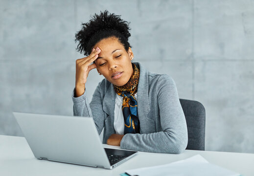 Portrait of a young black businesswoman havin a headache, or being stressed at work in the office. Overworked and sleepy frustrated business person